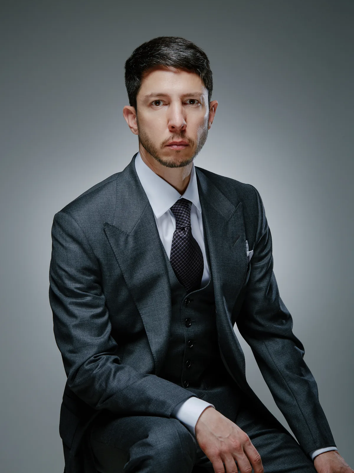 Cyrus Makarechian, seated, in a grey three-piece suit and tie